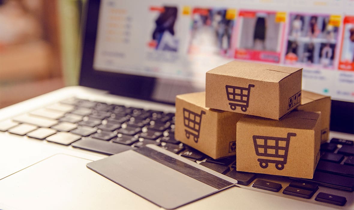 Shopping online. Cardboard box with a shopping cart logo in a trolley on a laptop keyboard payment by credit card and offers home delivery.