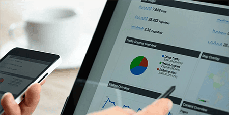 Charts and analytical data on the tablet screen with a cup of coffee and a telephone.