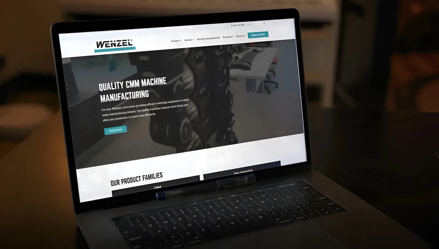 Laptop displaying Wenzel's quality CMM machine manufacturing homepage on a dark desk.